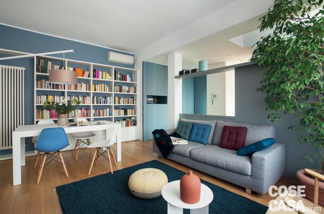 zona giorno open space del sottotetto su due livelli, tavolo da pranzo bianco, sedie design anni '50. libreria, radiatore d'arredo, divano grigio, tavolino bianco, parete divisoria di colore grigio-azzurro zona giorno open space del sottotetto su due livelli, tavolo da pranzo bianco, sedie design anni '50. libreria, radiatore d'arredo, divano grigio, tavolino bianco, parete divisoria di colore grigio-azzurro