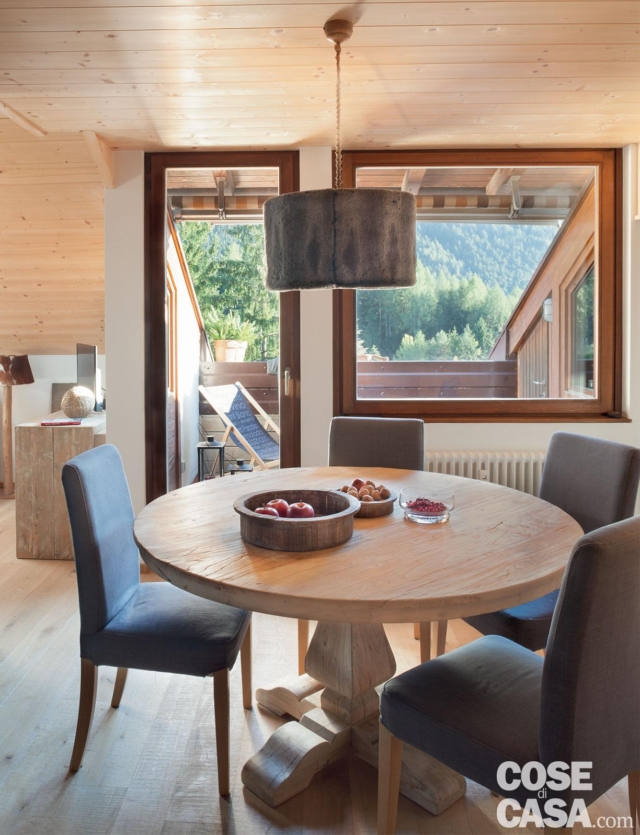 zona pranzo, tavolo rotondo in legno, sedie azzurre, terrazzo a tasca, portafinestra, finestra, lampada a sospensione cilindrica, parquet zona pranzo, tavolo rotondo in legno, sedie azzurre, terrazzo a tasca, portafinestra, finestra, lampada a sospensione cilindrica, parquet