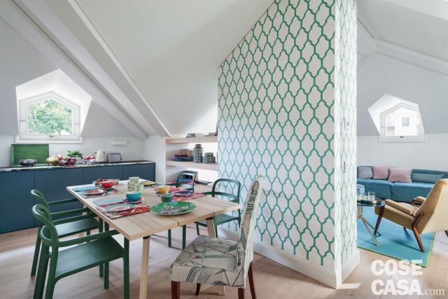 zona pranzo della mansarda ristrutturata, tavolo rettangolare, sedie verdi, carta da parati decorata, finestra a cappuccina, basi della cucina, pavimento in parquet zona pranzo della mansarda ristrutturata, tavolo rettangolare, sedie verdi, carta da parati decorata, finestra a cappuccina, basi della cucina, pavimento in parquet