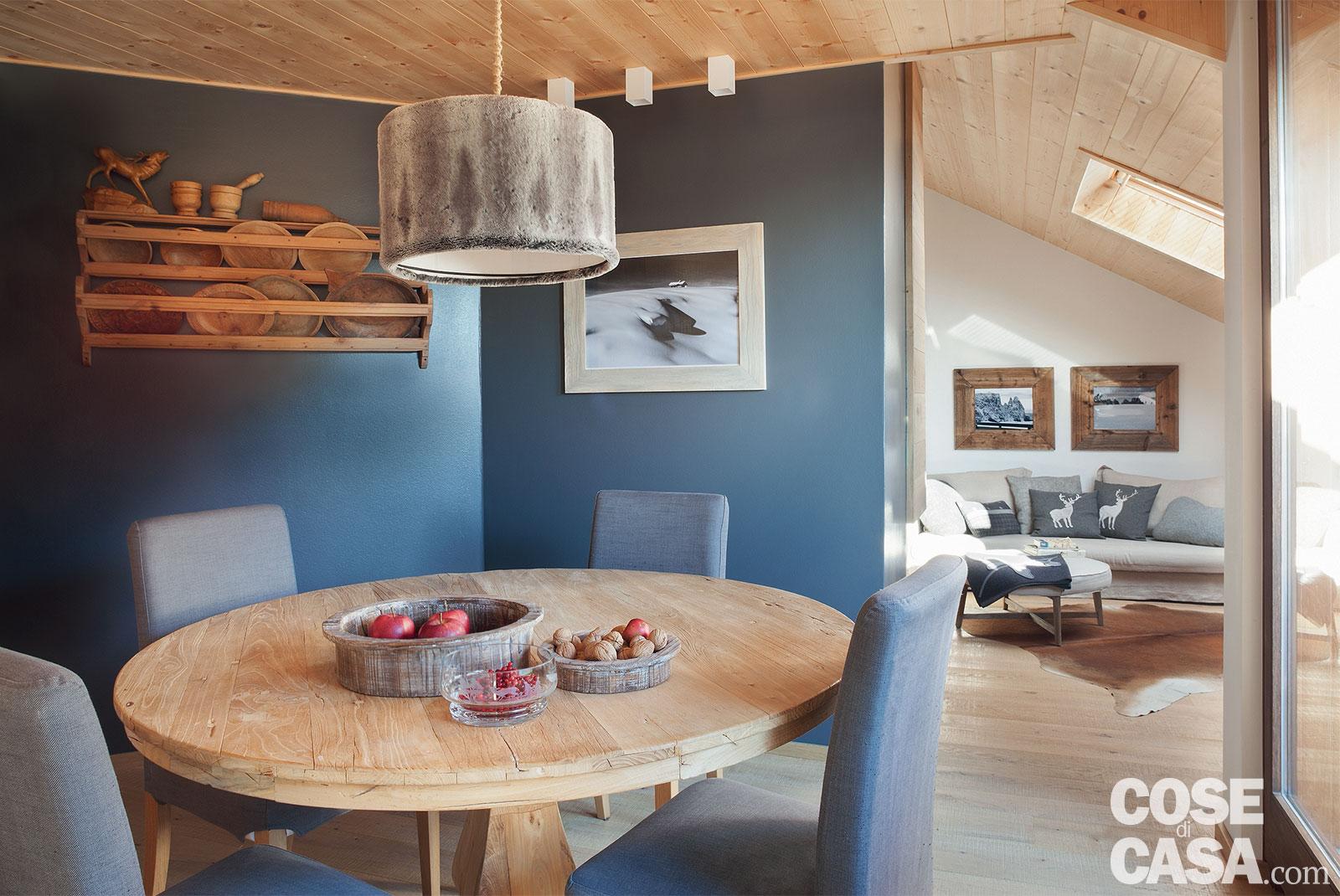 Intorno al tavolo da pranzo, le pareti sono
state tinteggiate con uno smalto grigio-azzurro opaco. Oltre che dalla sospensione centrale, l'ambiente è illuminato da tre faretti installati nel controsoffitto in legno. A parete, la foto con la neve incorniciata è opera di Mario Vidor.