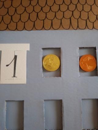 Attaccate le monete di cioccolate dentro ciascuna finestra con del nastro biadesivo