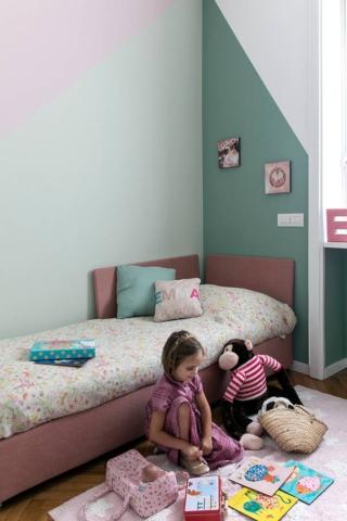 Cameretta bimba con parete a triangoli colorati e letto tessile