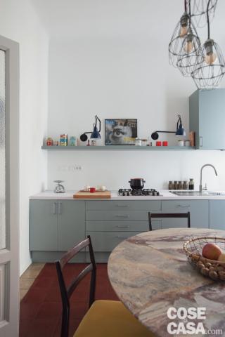 cucina, basi con piano cottura e lavello, mensola, pensili, tavolo rotondo con piano in marmo, sedie nere, sospensioni in metallo cucina, basi con piano cottura e lavello, mensola, pensili, tavolo rotondo con piano in marmo, sedie nere, sospensioni in metallo