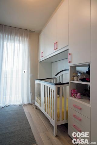 cameretta, lettino con sponde alte, armadio a ponte in laccato bianco opaco, finestra, tendaggi bianchi, passatoia, parquet