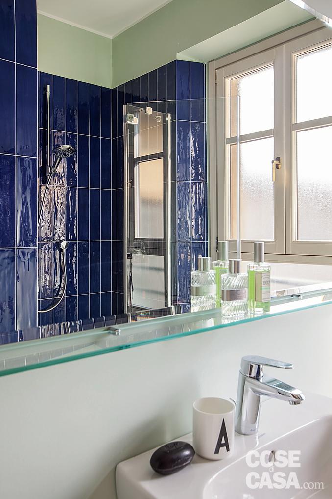 Nel box doccia le piastrelle Joyful color Navy di Tonalite sono posate in verticale. Il miscelatore del lavabo è di Ideal Standard.