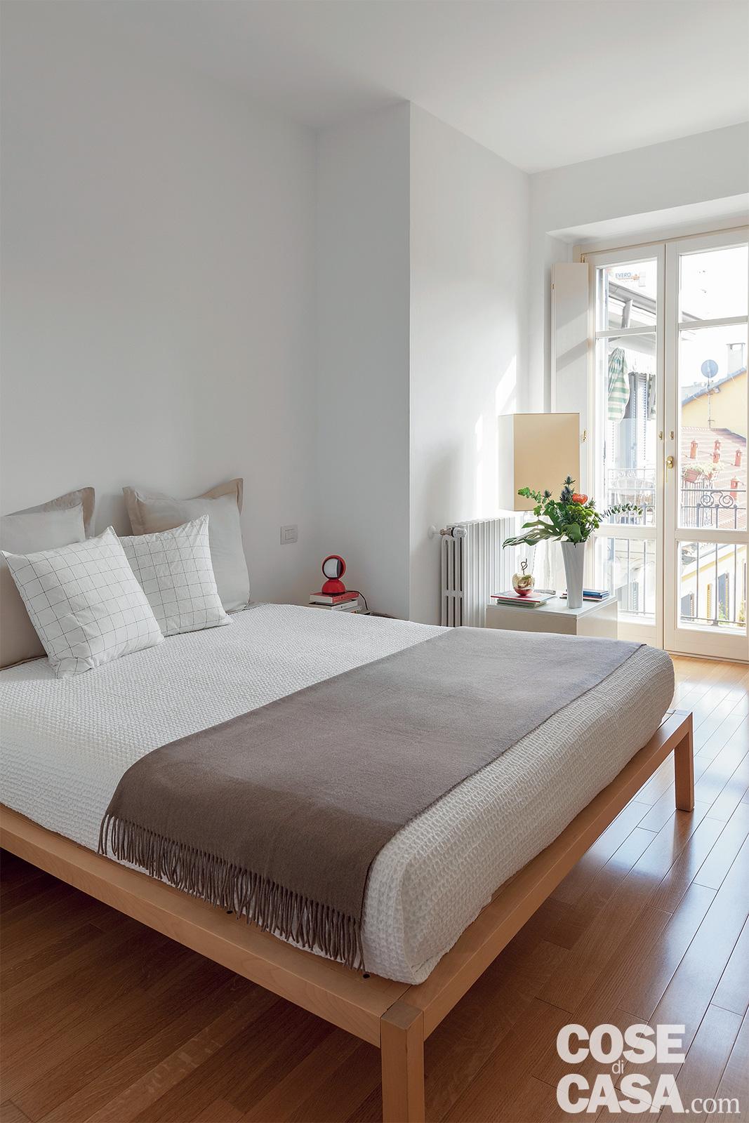 Sul letto matrimoniale con struttura in legno, il plaid e le federe dei cuscini sono di Zara Home, il copriletto di Fazzini: come si vede, per il tessile sono state privilegiate tinte soft.