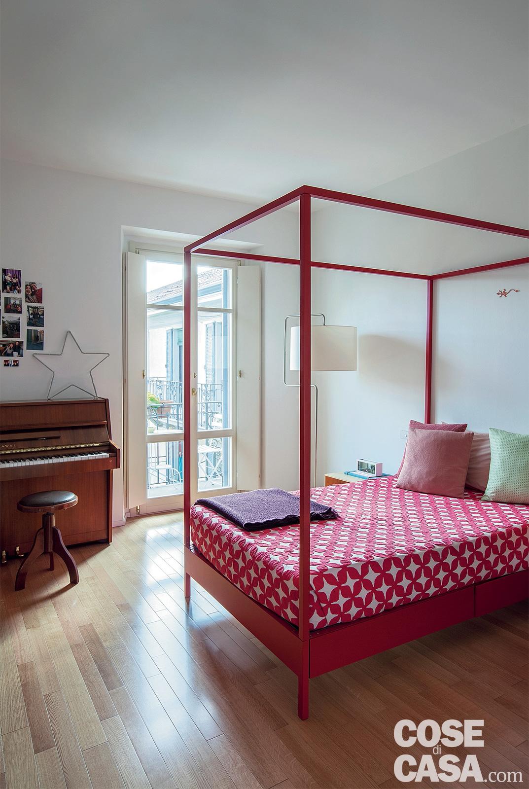 Nella camera dei ragazzi il letto è un modello a baldacchino in ferro verniciato rosso dalle linee contemporanee.