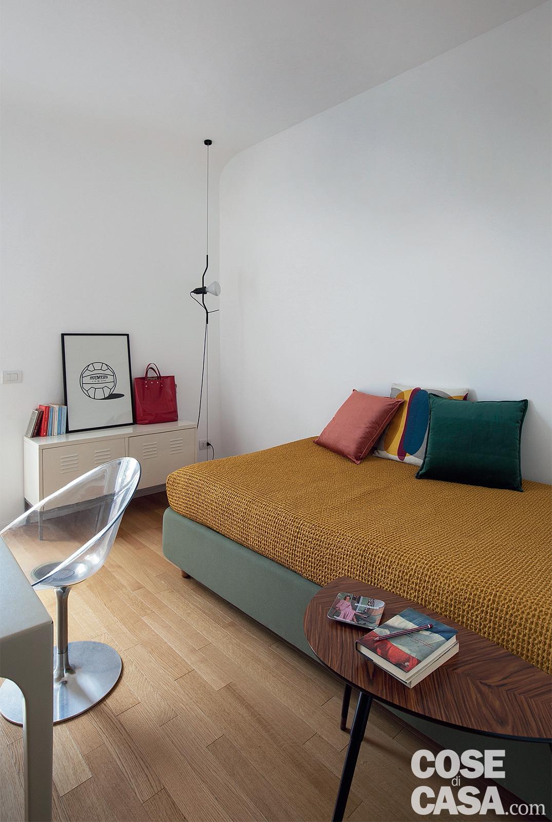 Nella stanza degli ospiti, unica delle tre camere affacciata verso Nord sul lato del terrazzo, la lampada a sospensione nell'angolo è la Parentesi di Flos, design Achille Castiglioni e Pio Manzù. Sul letto tessile appoggiato alla parete, copriletto e cuscini sono di Fazzini.