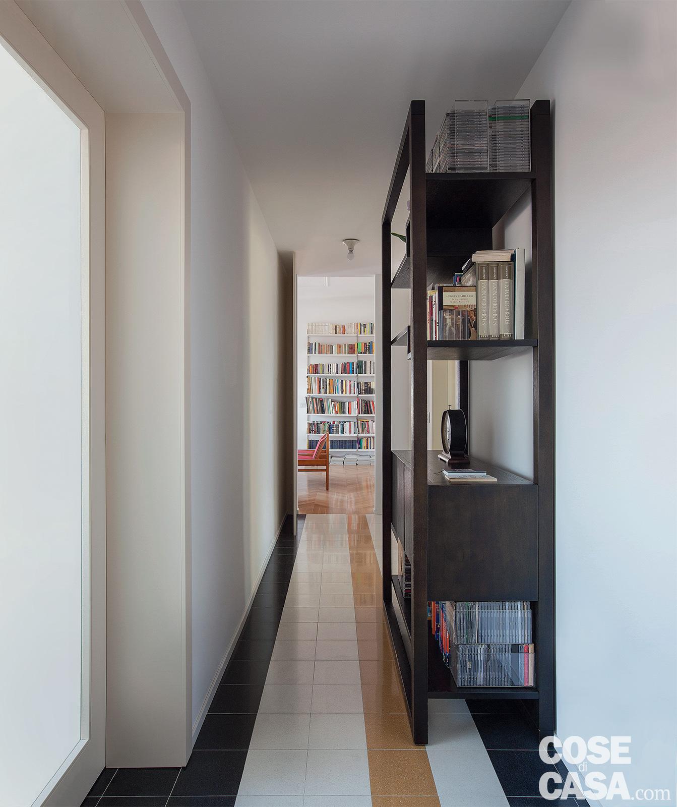 Nel corridoio, arredato con un mobile-libreria di modernariato le marmette in graniglia a pavimento sono di Mipa. La lampada a soffitto è Teti di Artemide, design Vico Magistretti.