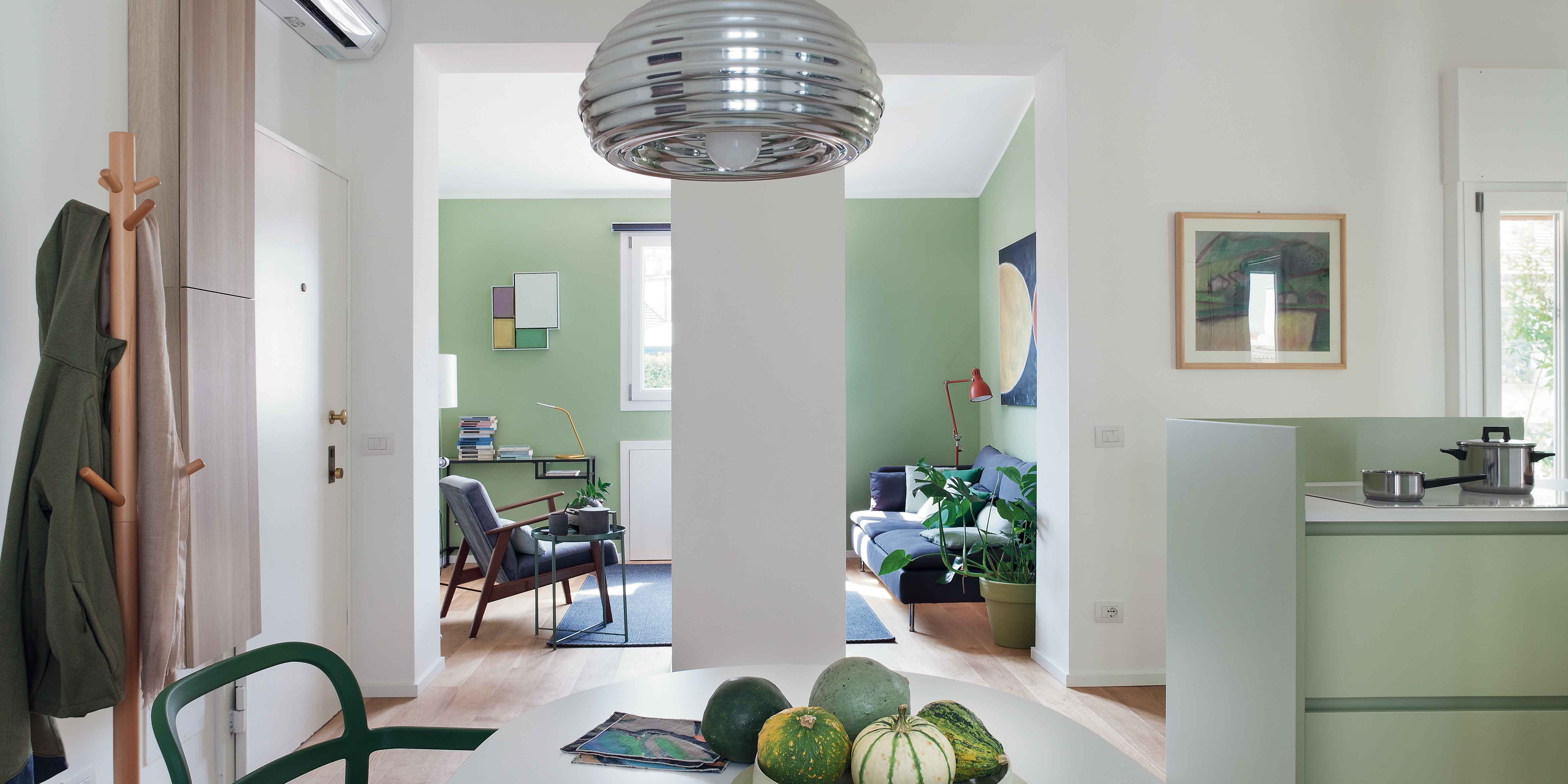 ingresso, zona pranzo, tavolo, sedie verdi, lampada a sospensione cromata, centrotavola con zucche, appendiabiti in legno, penisola della cucina, alzata verde, pilastro, climatizzatore split a parete