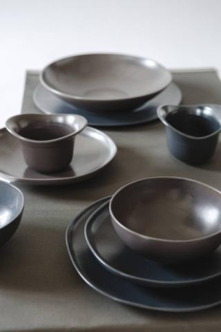 Una tonalità di grigio scurissimo per i piatti superchic della Grès Collection di SchoenhuberFranchi distribuiti da knIndustrie. La linea pura e le forme asimmetriche mettono in risalto la matericità del grès e la ricercata colorazione che dà vita a giochi di luce sulla superficie che ricordano il metallo. Il piatto fondo asimmetrico misura L 23 x P 21 cm, prezzo 21 euro. Il piatto fondo sky misura Ø 23 cm, prezzo 21 euro.  www.knindustrie.it