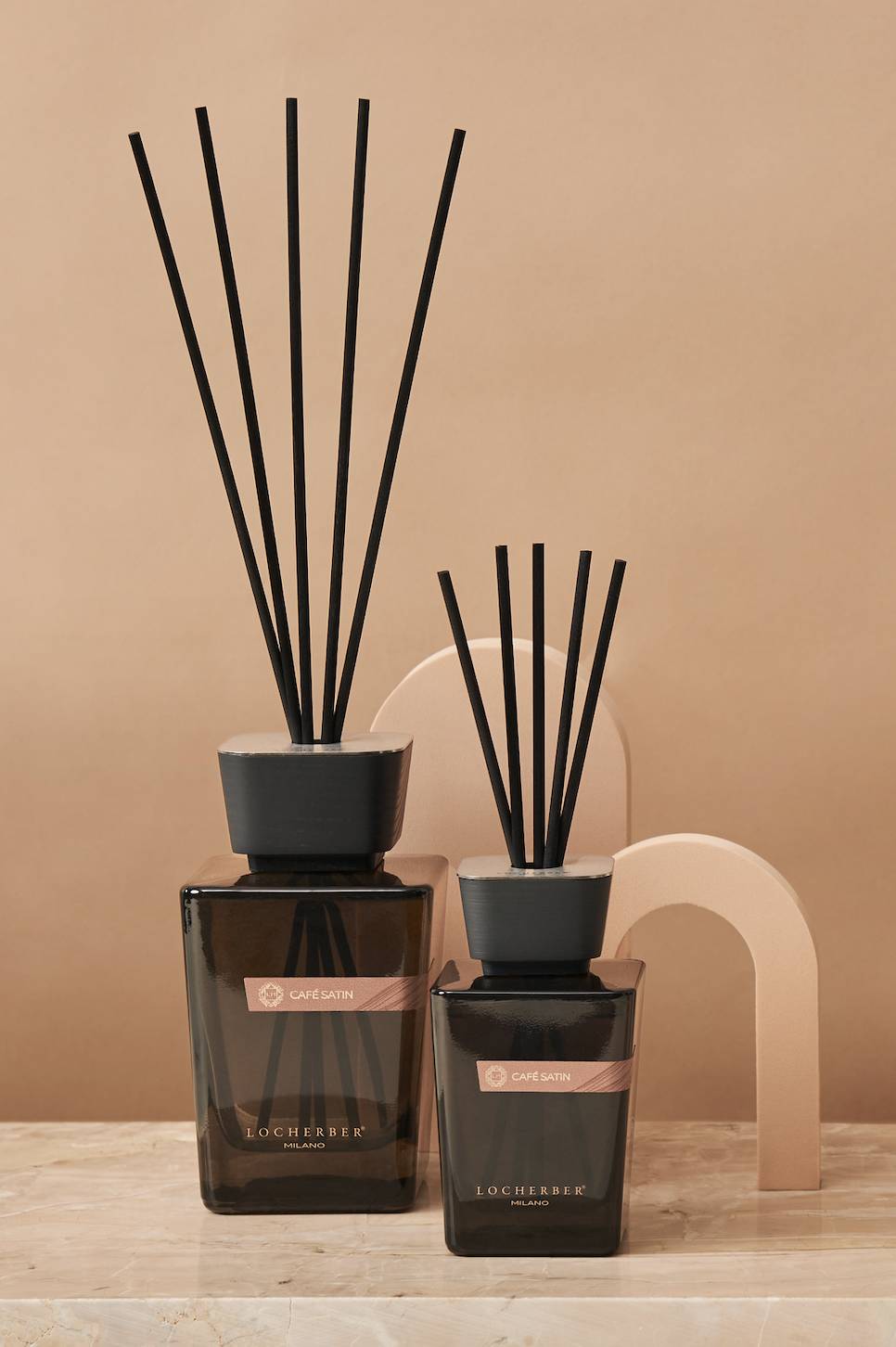 Avvolgente e seducente, Café Satin è la fragranza di Locherber Milano ispirata al caffè Gesha, una delle varietà di arabica più pregiate al mondo. Sofisticato e seducente, Café Satin  si apre con le note amaricanti, ma al tempo stesso avvolgenti e vellutate del caffè, per evolvere in un’esplosione di rosa e geranio, sino a chiudere con un finale dolce e caldo di vaniglia, ambra e muschio bianco. È disponibile in eleganti flaconi (di diversi formati da 250 ml a 5000 ml) realizzati da maestri vetrai italiani in vetro fumé scuro e impreziositi dall’iconico tappo T2 in frassino verniciato nero. Da 125 ml, prezzo 44 euro. www.locherbermilano.com