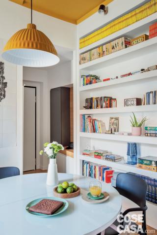 soggiorno del trilocale, zona pranzo, libreria in cartongesso, tavolo rotondo, sospensione gialla, sedie, vaso bianco, stoviglie, soffitto giallo soggiorno del trilocale, zona pranzo, libreria in cartongesso, tavolo rotondo, sospensione gialla, sedie, vaso bianco, stoviglie, soffitto giallo