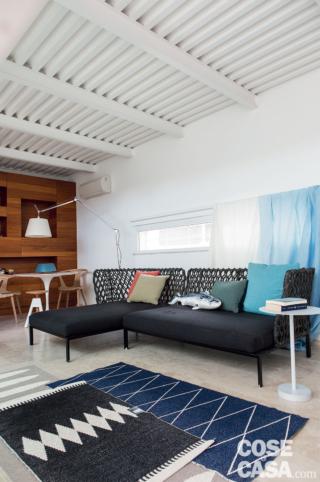 Nel luminoso soggiorno, affacciato sul patio e anche sul lato opposto, il divano modulare in composizione ad angolo è il modello Ravel di B&B Italia, design Patricia Urquiola; con schienale in polipropilene intrecciato, è progettato anche per l'outdoor. I cuscini di Muuto sono in vendita da Magazzini Associati. Alle spalle, la finestra a nastro - l'unica affacciata su strada - può essere schermata anziché dai classici tendaggi, da teli in lino bianchi e azzurri (di Designers Guild) semplicemente appoggiati sulla barra superiore. Sul piano del mobile basso in laccato bianco, la lampada è Uovo di FontanaArte. Nel luminoso soggiorno, affacciato sul patio e anche sul lato opposto, il divano modulare in composizione ad angolo è il modello Ravel di B&B Italia, design Patricia Urquiola; con schienale in polipropilene intrecciato, è progettato anche per l'outdoor. I cuscini di Muuto sono in vendita da Magazzini Associati. Alle spalle, la finestra a nastro - l'unica affacciata su strada - può essere schermata anziché dai classici tendaggi, da teli in lino bianchi e azzurri (di Designers Guild) semplicemente appoggiati sulla barra superiore. Sul piano del mobile basso in laccato bianco, la lampada è Uovo di FontanaArte.