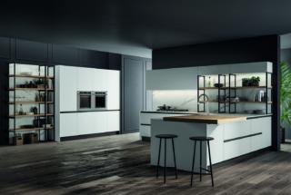 Kalì, composizione con penisola con piano snack, basi Pet maxximatt opaco bianco con maniglia 1600 Profilo e zoccolo alluminio titanio; libreria Factory struttura alluminio titanio, mensole laminato rovere biondo.