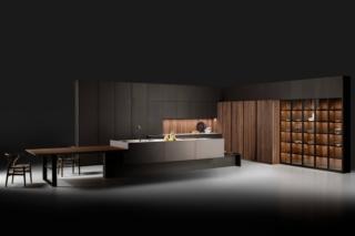 Il nuovo modello Strip di Key Cucine, design Nevio Tellatin, coniuga insieme funzionalità e ricerca estetica, compenetrando insieme la zona operativa e il salotto. Le ante sono in pregiato Noce Canaletto, con una fresatura verticale che dona alla superficie un aspetto lussuoso, e in metallo liquido nella finitura soft touch che le rende piacevoli al tatto. Il piano è in marmo Mustang con un trattamento della superficie che lo protegge; è presente un tavolo effetto sospeso in legno. Le colonne a vetri sono dotate di un ripiano luminoso in metallo titanio con basamento in vetro dove è inserito un led nella parte frontale, mentre i pensili sono dotati di una barra a led inserita nel fondo. www.keycucine.it Fuorisalone, Showroom di Agape 12, via Statuto 12, Milano