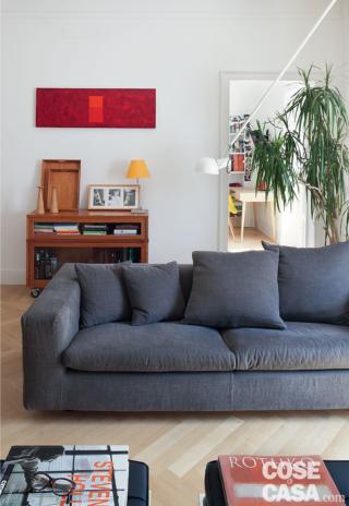 Nella zona conversazione del living, illuminata da una portafinestra, il divano rivestito in tessuto grigio è di Flexform; la poltroncina arancione e altri complementi si rifanno a classici del design degli anni '50. Il parquet in rovere è posato con geometria a spina di pesce all'italiana. Nella zona conversazione del living, illuminata da una portafinestra, il divano rivestito in tessuto grigio è di Flexform; la poltroncina arancione e altri complementi si rifanno a classici del design degli anni '50. Il parquet in rovere è posato con geometria a spina di pesce all'italiana.