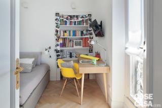 camera dei ragazzi, letto tessile, copriletto grigio, porta, scrivania, sedia gialla, libreria a giorno in nicchia, portafinestra, applique da lettura, applique cubiche, parquet a spina di pesce camera dei ragazzi, letto tessile, copriletto grigio, porta, scrivania, sedia gialla, libreria a giorno in nicchia, portafinestra, applique da lettura, applique cubiche, parquet a spina di pesce