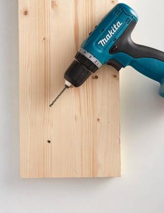 Carteggiare la superficie dell’asse di legno e livellarla fino a renderla perfettamente liscia. Con l'aiuto della matita e del righello riportare lo schema di fissaggio delle valvole: fissare punti equidistanti, sfalsati e non perfettamente allineati, così da ottenere una composizione equilibrata in grado di ospitare tutti gli accessori e gli abiti da appendere. Forare il legno nei punti prefissati con il trapano elettrico, utilizzando una punta leggermente più grande di quella delle viti. La punta dovrà muoversi perpendicolarmente rispetto all’asse, forandola per metà del suo spessore, senza raggiungere il retro e senza oltrepassarla completamente.