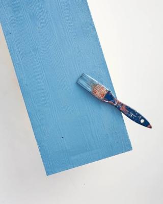 Quando il primer è asciutto, ripetere l’operazione con il colore azzurro denim, stendendolo in modo uniforme e poco diluito per ottenere una colorazione piena e corposa, ben coprente. Dipingere anche il retro e gli spessori utilizzando il pennello a punta piatta oppure il rullo da pittura; lasciare asciugare tra una stesura e l’altra. Ripetere il procedimento se necessario.