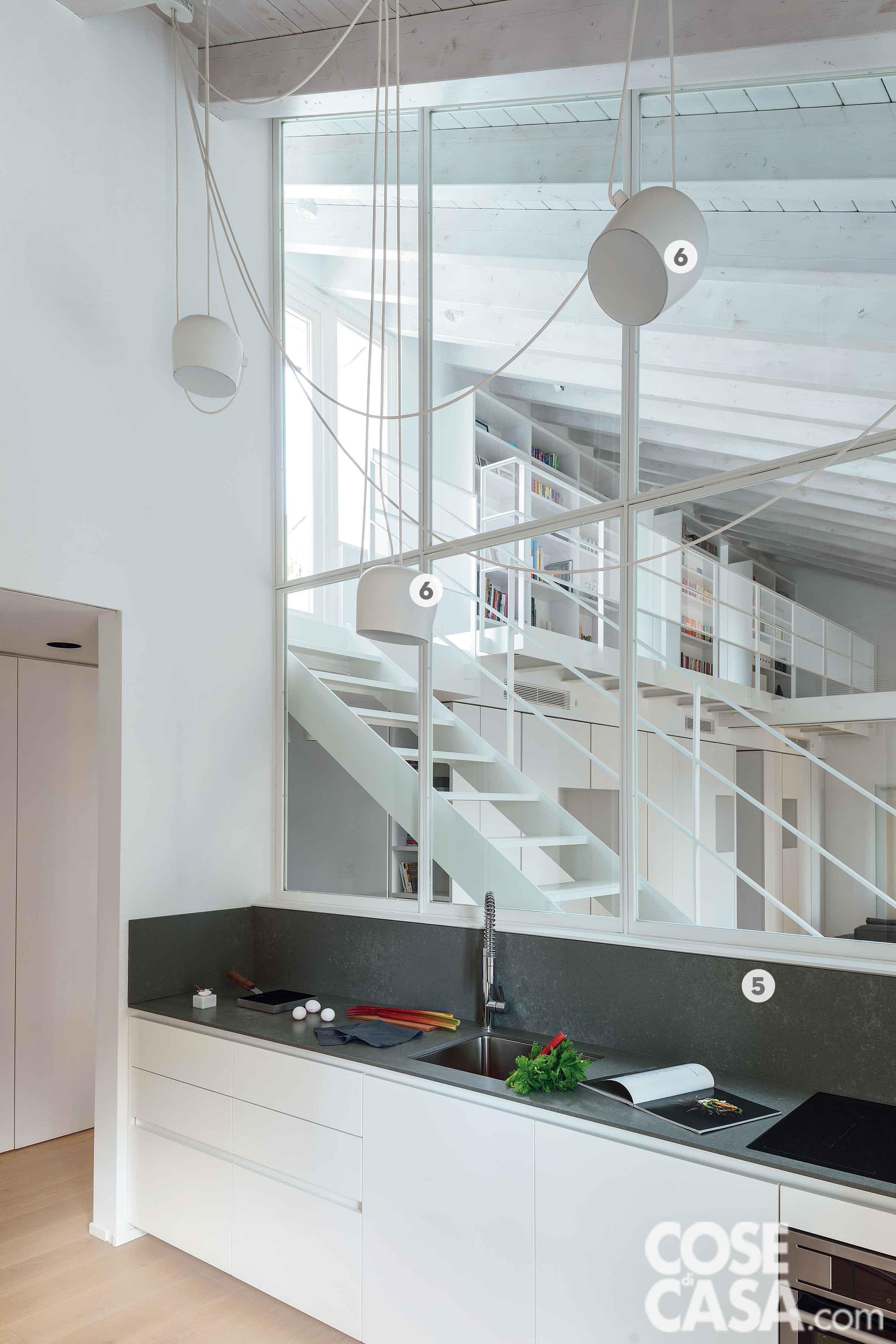 La cucina, oltre la vetrata che la divide dal living, è illuminata dal sistema di lampade a sospensione Aim di Flos in finitura bianca. Nella composizione di Ernestomeda, il lato con la zona lavaggio e il piano cottura a induzione affaccia verso il living. Il lavello in acciaio inox (di Blanco, con miscelatore di Gessi), è integrato sottotop nel piano in pietra naturale. La padella a sinistra sul top The Omelette di Kn Industrie, la saliera è Half Moon di Paola C. Nel sottotetto e sul soppalco, tutte le opere in ferro sono state realizzate da Milano Ecostrutture. La cucina, oltre la vetrata che la divide dal living, è illuminata dal sistema di lampade a sospensione Aim di Flos in finitura bianca. Nella composizione di Ernestomeda, il lato con la zona lavaggio e il piano cottura a induzione affaccia verso il living. Il lavello in acciaio inox (di Blanco, con miscelatore di Gessi), è integrato sottotop nel piano in pietra naturale. La padella a sinistra sul top The Omelette di Kn Industrie, la saliera è Half Moon di Paola C. Nel sottotetto e sul soppalco, tutte le opere in ferro sono state realizzate da Milano Ecostrutture.