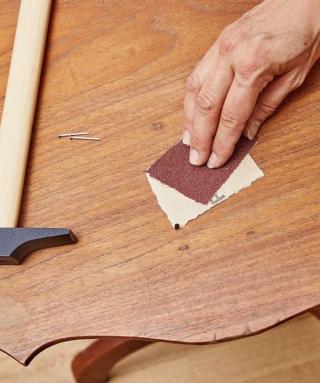 Dopo aver rimosso con la pinza eventuali chiodi o pezzi di ferro, carteggiare la superfice del tavolino con carta vetrata di grana media, così da eliminare imperfezioni, schegge ed eventuali residui di vernice. Ripassare con un panno pulito per rimuovere la polvere e la segatura generate durante l'operazione. Se necessario, fissare le parti poco stabili con chiodini o colla per legno.