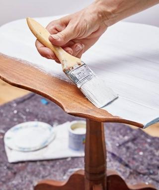 Lavorando sopra un piano protetto con vecchi stracci, carta da pacco o fogli di giornale, stendere una mano di fondo bianco per pittura acrilica sull'intera superfcie, avendo cura di ricoprire bene anche le zone a rilievo o intagliate. Lasciare asciugare completamente, quindi passare una seconda mano in modo da ottenere una base uniforme per facilitare la stesura del prodotto che farà da finitura.