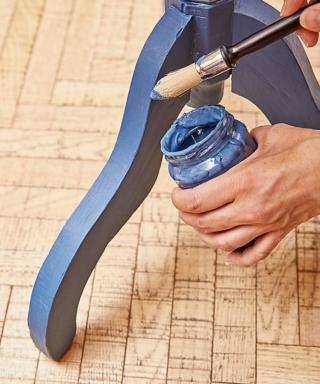 Utilizzando il pennello grande a punta tonda, stendere una velatura uniforme di colore bluette sulla parte bassa della gamba centrale e sui piedi laterali. Una volta asciutta, ripetere l’operazione prestando attenzione alle parti lavorate. Trascorse 24 ore, disporre il tavolino a testa in giù per ultimare il lavoro sul retro.