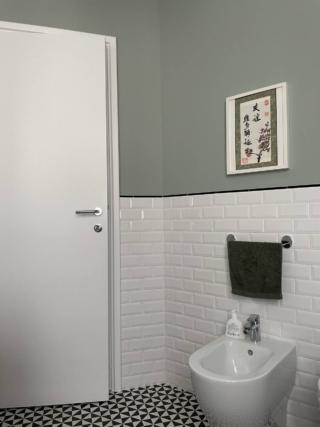 bagno con piastrelle diamantate bianche, pittura verde salvia,  bidet, portasciugamani nero e quadretto centrato sopra bagno con piastrelle diamantate bianche, pittura verde salvia,  bidet, portasciugamani nero e quadretto centrato sopra