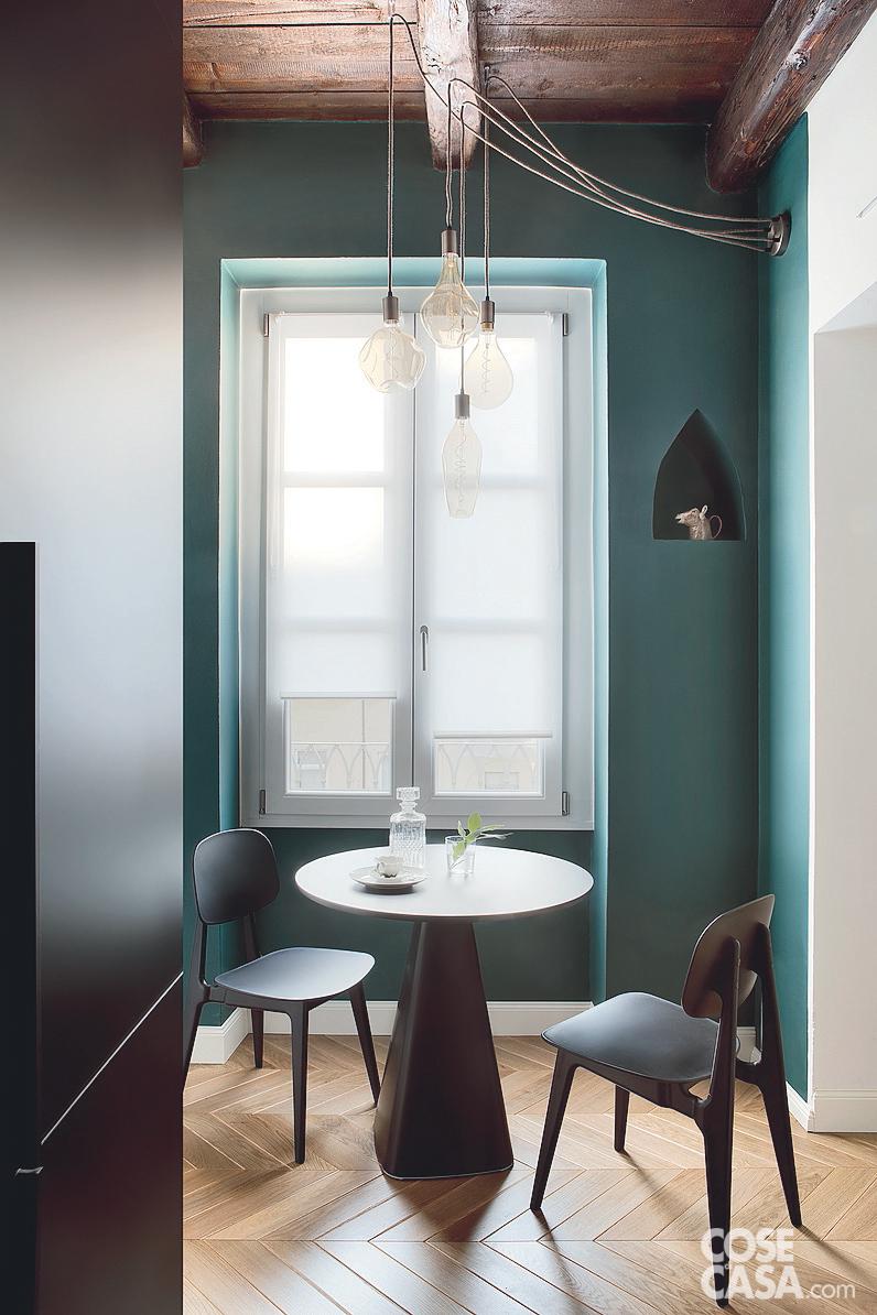 zona pranzo, finestra, tende a pacchetto, lampadario destrutturato, tavolo rotondo con base a cono, sedie nere, parquet a spina di pesce, soffitto con travi a vista zona pranzo, finestra, tende a pacchetto, lampadario destrutturato, tavolo rotondo con base a cono, sedie nere, parquet a spina di pesce, soffitto con travi a vista