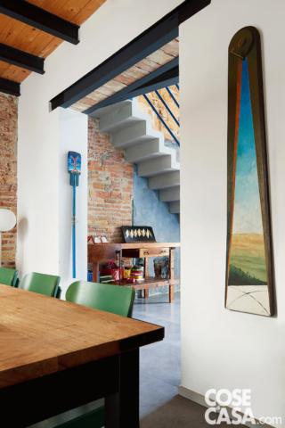zona giorno del sottotetto, scala con ringhiera in ferro, travi, copertura in legno, muri in mattoni faccia a vista dettaglio del tavolo e delle sedie, pavimento in cemento zona giorno del sottotetto, scala con ringhiera in ferro, travi, copertura in legno, muri in mattoni faccia a vista dettaglio del tavolo e delle sedie, pavimento in cemento