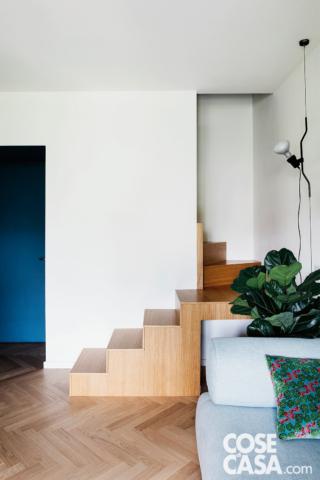 dettaglio della scala della mansarda, gradini in legno, parquet a spina di pesce, lampada a sospensione di design, divano