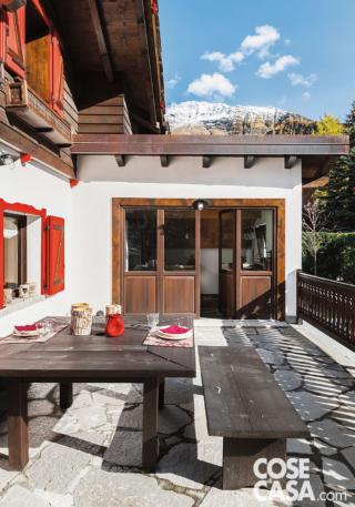 esterno dello chalet, terrazzo, finestre con scuri esterni, portafinestra a quattro ante, balaustra, tavolo da pranzo, panchetta, pavimento in pietra, tetto in legno