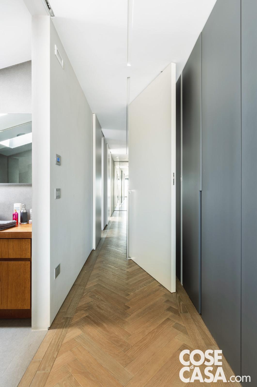 Nel controsoffitto del corridoio sono stati praticati due sottili tagli, divisi in corrispondenza del serramento: all'interno sono inseriti profili in gesso con strip led.
La porta a bilico, larga 120 cm e incernierata a 20 cm circa dallo stipite, si apre e si chiude con una maniglia verticale in acciaio. Sulla parete le placche con gli interruttori sono di BTicino, come nel resto dell'abitazione. Nel controsoffitto del corridoio sono stati praticati due sottili tagli, divisi in corrispondenza del serramento: all'interno sono inseriti profili in gesso con strip led.
La porta a bilico, larga 120 cm e incernierata a 20 cm circa dallo stipite, si apre e si chiude con una maniglia verticale in acciaio. Sulla parete le placche con gli interruttori sono di BTicino, come nel resto dell'abitazione.