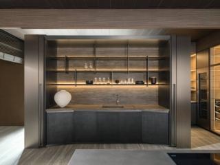 La cucina Tivalì 2.0 di Dada si articola in uno spazio lineare tra i 2,40 e i 3 metri e può essere chiusa in un mobile con due grandi ante scorrevoli a pacchetto, che una volta aperte, rientrano affiancandosi nella sagoma del contenitore grazie a sofisticati meccanismi e all'assenza del basamento e del carrello inferiore. La composizione è configurabile in tre diverse altezze e due larghezze; sono possibili infinite possibilità di configurazione interna. Le basi ad “anfiteatro” e il piano di lavoro arcuato in marmo o pietra rendono la cucina scenografica; lo schienale rivestito in marmo presenta una scaffalatura con un sistema di led integrati nelle mensole. www.dada-kitchens.com