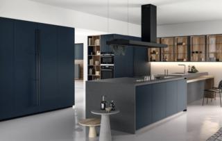 Un'intensa tonalità di blu scuro per le ante lisce, con maniglia godronata verticale o apertura push-pull, in laccato opaco della cucina Time 03 di Arredo3 che si apre sulla zona giorno. I pensili a parete in noce Imperial con le ante Teca in vetro trasparente consentono di esporre oggetti e stoviglie e alleggeriscono la composizione. L'isola centrale si articola in due corpi e ha il piano di lavoro in Cosmolite star grey uniti da una struttura di mensole. Prezzo su richiesta. www.arredo3.it Un'intensa tonalità di blu scuro per le ante lisce, con maniglia godronata verticale o apertura push-pull, in laccato opaco della cucina Time 03 di Arredo3 che si apre sulla zona giorno. I pensili a parete in noce Imperial con le ante Teca in vetro trasparente consentono di esporre oggetti e stoviglie e alleggeriscono la composizione. L'isola centrale si articola in due corpi e ha il piano di lavoro in Cosmolite star grey uniti da una struttura di mensole. Prezzo su richiesta. www.arredo3.it