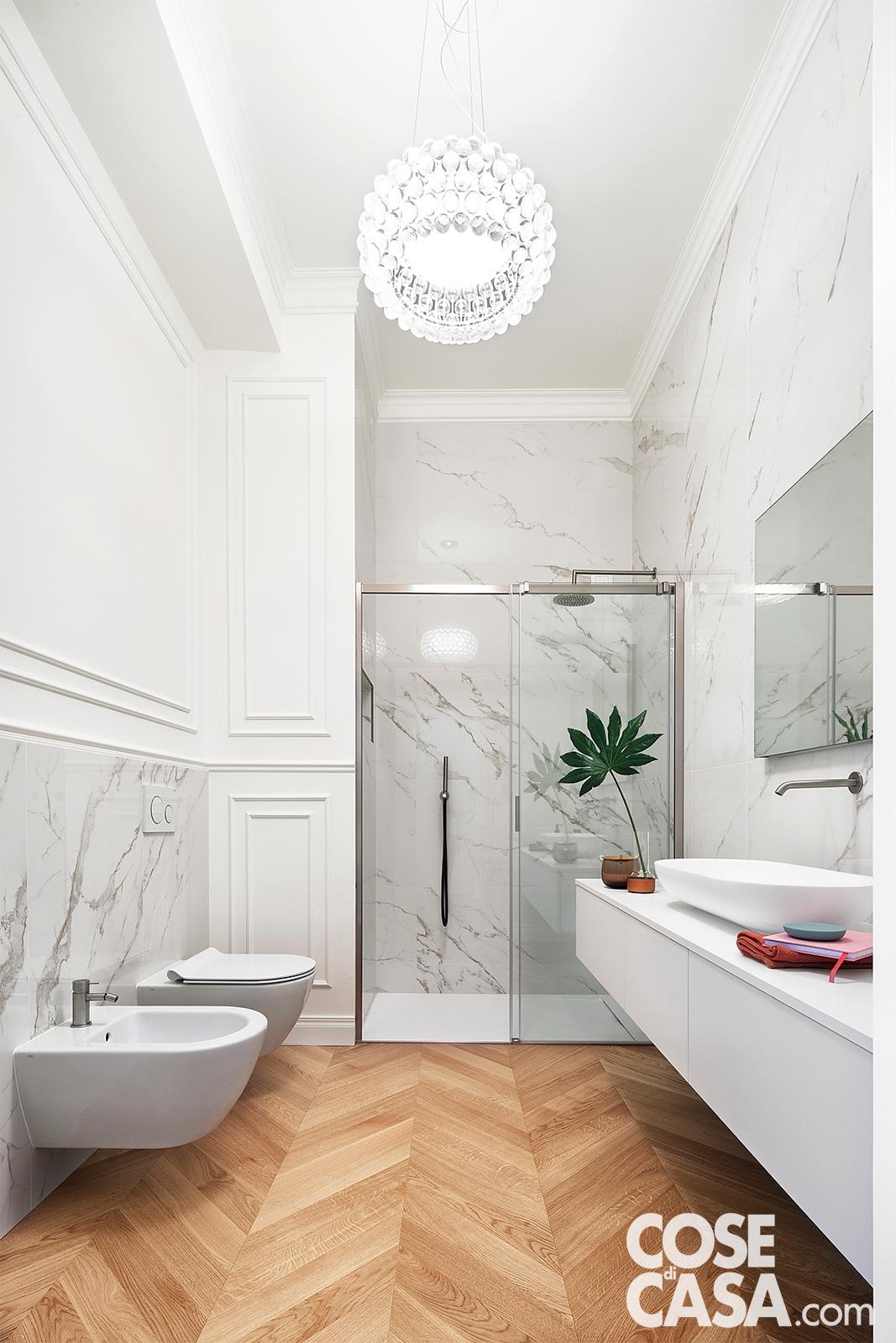 bagno con doccia in marmo bianco carrara e pavimento in parquet a spina di pesce