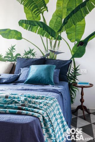 camera matrimoniale, letto, completo biancheria sui toni dell'azzurro, cuscini, tavolino rotondo, disegno jungle a parete, piastrelle triangolari a pavimento camera matrimoniale, letto, completo biancheria sui toni dell'azzurro, cuscini, tavolino rotondo, disegno jungle a parete, piastrelle triangolari a pavimento