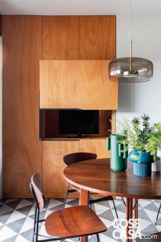 zona giorno del bilocale, tavolo da pranzo, mobile con zona tv a scomparsa, sedie, lampada a sospensione, piastrelle triangolari, vasi colorati appoggiati sul piano zona giorno del bilocale, tavolo da pranzo, mobile con zona tv a scomparsa, sedie, lampada a sospensione, piastrelle triangolari, vasi colorati appoggiati sul piano