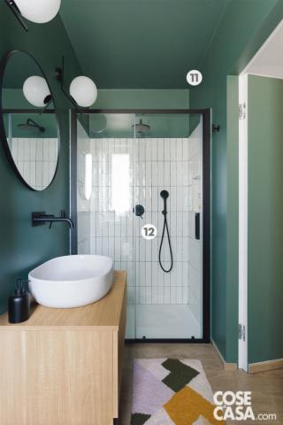 Il rivestimento a terra e lo zoccolino sono in gres porcellanato effetto legno, le pareti sono trattate con pittura bicomponente di Sikkens. Le piastrelle rettangolari all'interno del box doccia sono di Iperceramica. La porta rasomuro è della serie Pantoquadra di Bertolotto. Rubinetteria nera a placca Gun di Jacuzzi, radiatore di Cordivari.