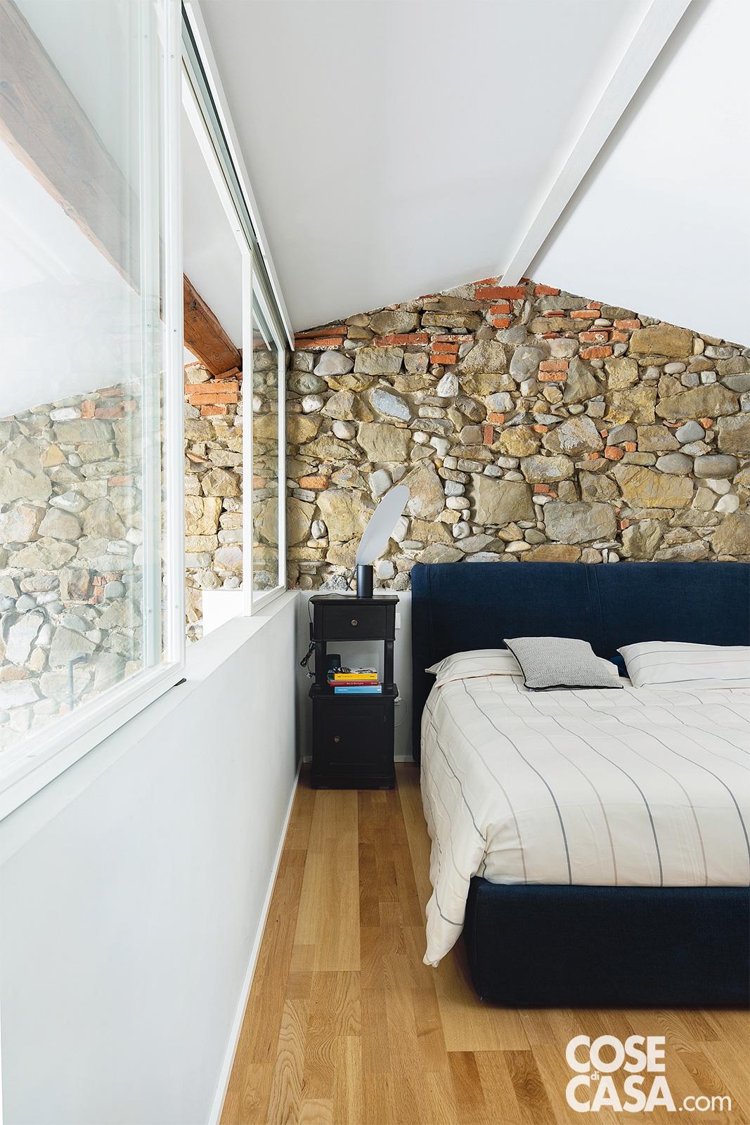 Affiancato da comodini d'epoca, il letto tessile di linea semplice è vestito con una parure a motivo rigato di Fazzini. Affiancato da comodini d'epoca, il letto tessile di linea semplice è vestito con una parure a motivo rigato di Fazzini.