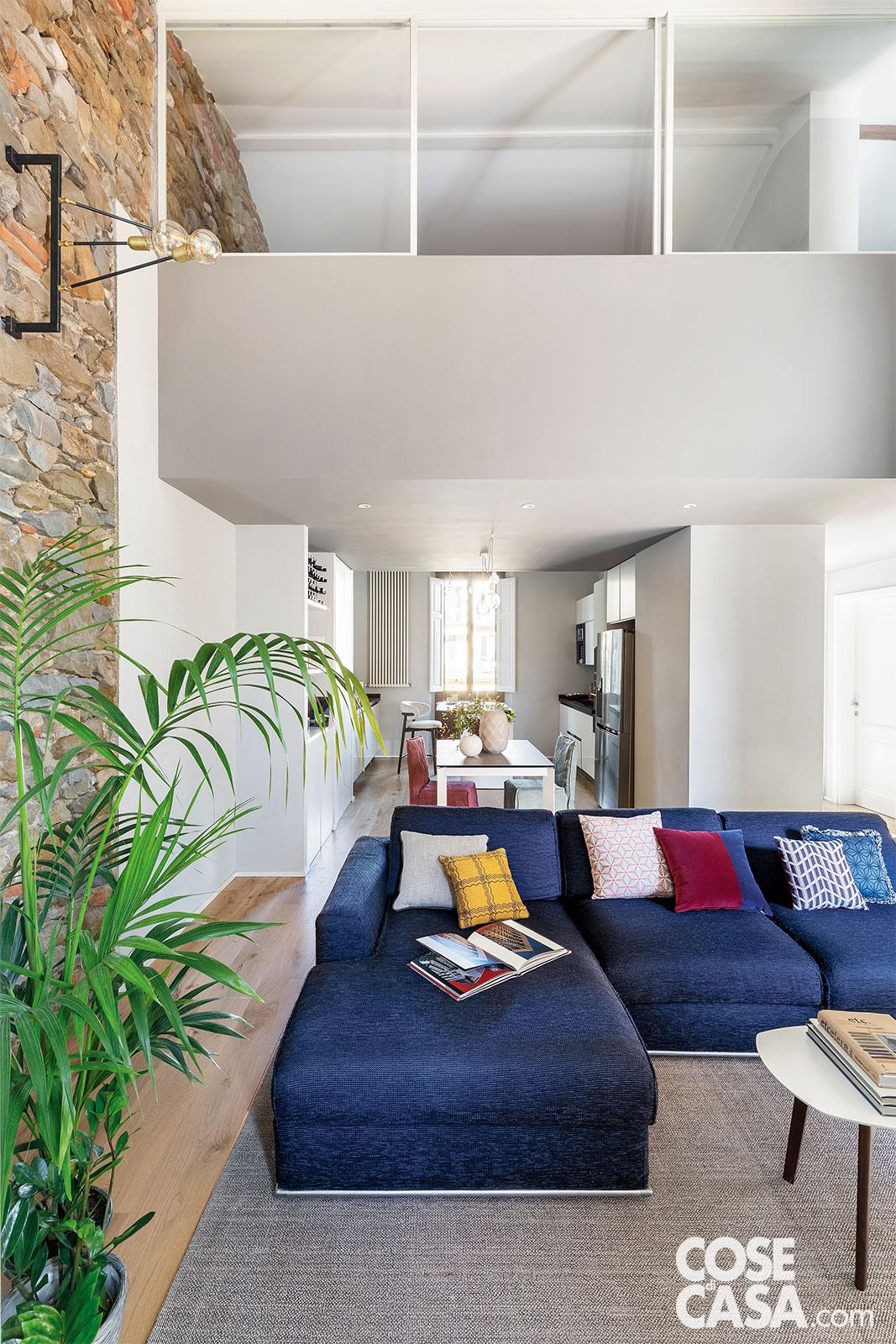 I volumi geometrici del soppalco, che sovrasta la zona giorno open space, dominano l'area centrale della casa. Il taglio di questo ambiente è pensato per trovare comoda collocazione all’importante divano di famiglia, rivestito in tessuto blu navy e ravvivato da cuscini colorati di L'Opificio. Lo corredano un maxi tappeto grigio-beige di GT Design e un tavolino di Calligaris. Nella zona pranzo, le sedie sono di Gervasoni, gli oggetti di Bosa. I volumi geometrici del soppalco, che sovrasta la zona giorno open space, dominano l'area centrale della casa. Il taglio di questo ambiente è pensato per trovare comoda collocazione all’importante divano di famiglia, rivestito in tessuto blu navy e ravvivato da cuscini colorati di L'Opificio. Lo corredano un maxi tappeto grigio-beige di GT Design e un tavolino di Calligaris. Nella zona pranzo, le sedie sono di Gervasoni, gli oggetti di Bosa.