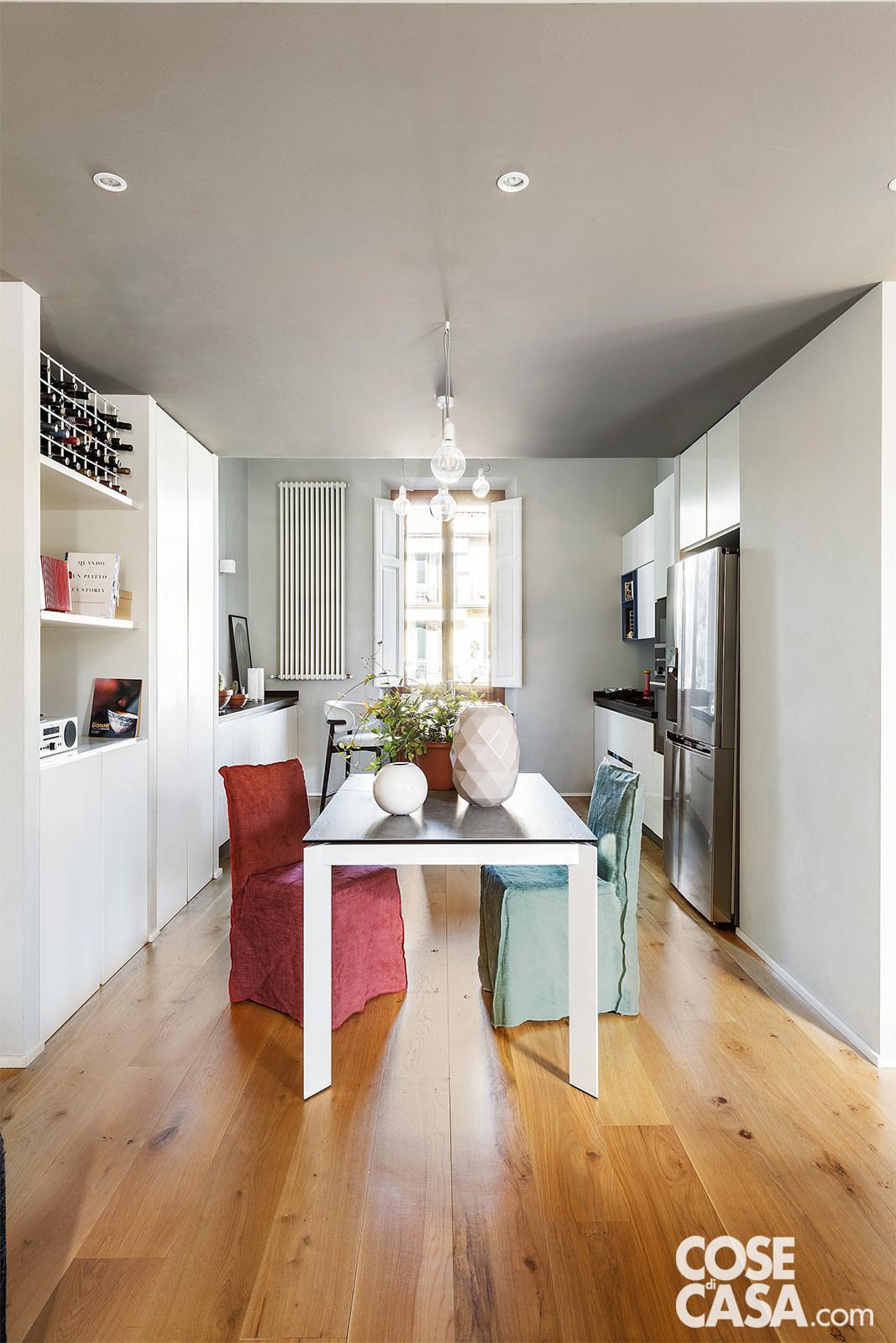 Nella parte del soggiorno che ospita la cucina con area pranzo adiacente, le pareti color grigio chiaro e il parquet in listoni di legno di rovere massello di Devon&Devon, trattato in opera, sono la giusta cornice per mettere in risalto gli arredi total white, su cui spiccano le note di colore introdotte dalle sedie habillé. In continuità con la cucina, la zona pranzo si concede nelle sedie un tocco décor. Sulla destra, l'inserimento del frigorifero a doppia porta ha richiesto una nicchia in muratura ad hoc. Sul fronte opposto, nell'ingresso, il vano di risulta è stato attrezzato come guardaroba. Nella parte del soggiorno che ospita la cucina con area pranzo adiacente, le pareti color grigio chiaro e il parquet in listoni di legno di rovere massello di Devon&Devon, trattato in opera, sono la giusta cornice per mettere in risalto gli arredi total white, su cui spiccano le note di colore introdotte dalle sedie habillé. In continuità con la cucina, la zona pranzo si concede nelle sedie un tocco décor. Sulla destra, l'inserimento del frigorifero a doppia porta ha richiesto una nicchia in muratura ad hoc. Sul fronte opposto, nell'ingresso, il vano di risulta è stato attrezzato come guardaroba.