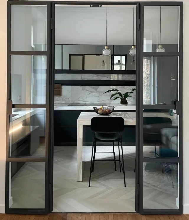 Effetto elegante: i mobili neri delle basi abbinati al marmo di Calacatta, con le sue venature dorate molto evidenti, e i pensili in vetro specchiato creano un insieme molto sobrio e armonico, con una sua eleganza non ostentata.