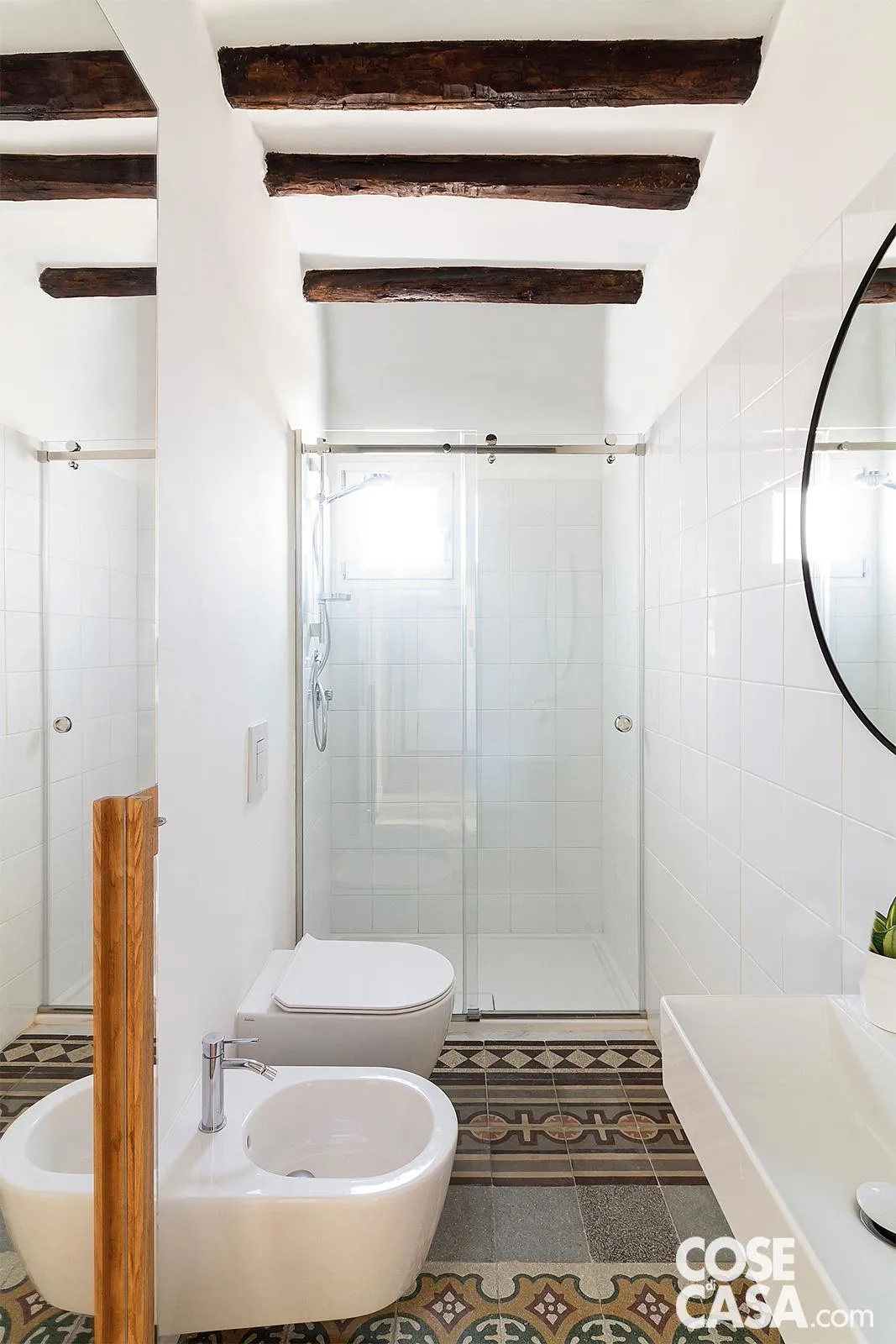 In questo bagno cieco la pavimentazione in cementine originali d’epoca - che prosegue senza interruzioni dal corridoio - è illuminata dal contrasto con le pareti total white. Le travi a vista, trattate per mantenere il fascino naturale del legno, dialogano con elementi neri a contrasto, come la cornice dello specchio e i profili della doccia, aggiungendo ritmo e carattere. In questo bagno cieco la pavimentazione in cementine originali d’epoca - che prosegue senza interruzioni dal corridoio - è illuminata dal contrasto con le pareti total white. Le travi a vista, trattate per mantenere il fascino naturale del legno, dialogano con elementi neri a contrasto, come la cornice dello specchio e i profili della doccia, aggiungendo ritmo e carattere.