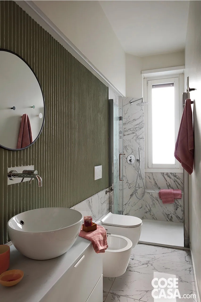 Bagno lungo e stretto, mantenuto nelle dimensioni originali e rinnovato con nuovi rivestimenti e sanitari sospesi compatti. Il piccolo lavabo d’appoggio è valorizzato da una scenografica parete a effetto cannettato. Pavimento e zona doccia sono rivestiti in gres effetto marmo di Carrara, che amplifica luminosità e percezione di spazio. Bagno lungo e stretto, mantenuto nelle dimensioni originali e rinnovato con nuovi rivestimenti e sanitari sospesi compatti. Il piccolo lavabo d’appoggio è valorizzato da una scenografica parete a effetto cannettato. Pavimento e zona doccia sono rivestiti in gres effetto marmo di Carrara, che amplifica luminosità e percezione di spazio.