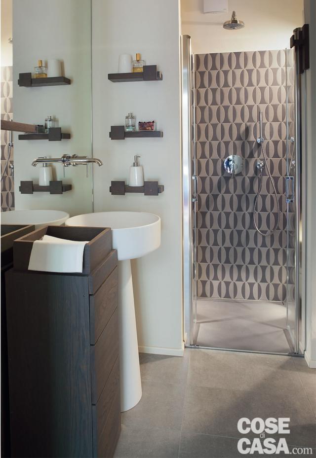 Uno specchio a tutta altezza dietro il lavabo amplifica la percezione dello spazio in questo bagno piccolo, mentre il rivestimento 3D tono su tono nella doccia aggiunge movimento. Mobili e mensole in legno scuro introducono un contrasto caldo e raffinato. Uno specchio a tutta altezza dietro il lavabo amplifica la percezione dello spazio in questo bagno piccolo, mentre il rivestimento 3D tono su tono nella doccia aggiunge movimento. Mobili e mensole in legno scuro introducono un contrasto caldo e raffinato.