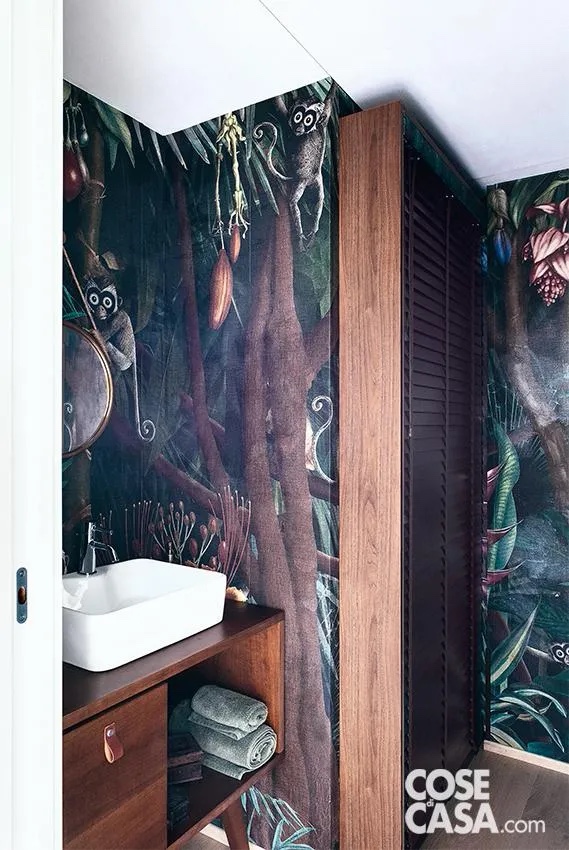 Nel piccolo bagno dalla allure esotica,, la presenza del legno scalda l’ambiente e lo avvicina alla natura, tema presente nella carta da parati con fogliame tropicale. L’insieme crea un equilibrio tra intimità e scenografia, con una forte identità stilistica. Nel piccolo bagno dalla allure esotica,, la presenza del legno scalda l’ambiente e lo avvicina alla natura, tema presente nella carta da parati con fogliame tropicale. L’insieme crea un equilibrio tra intimità e scenografia, con una forte identità stilistica.