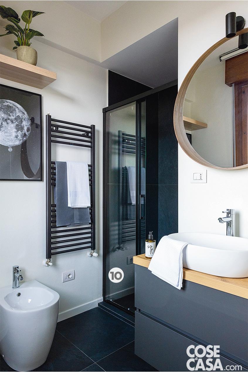 Nel bagno della camera matrimoniale il pavimento e l'interno della doccia sono rivestiti con lastre da 60 x 120 cm in gres WaterFall di Lea Ceramiche, finitura Dark Flow. I sanitari sono di Azzurra, la rubinetteria cromata è il modello Stick di Paffoni. Il mobile lavabo è stato acquistato online su Deghi, lo specchio è di Ikea. La barra a led nel box doccia è Cartoon Light di Novalux. Gli asciugamani sono di Gabel.