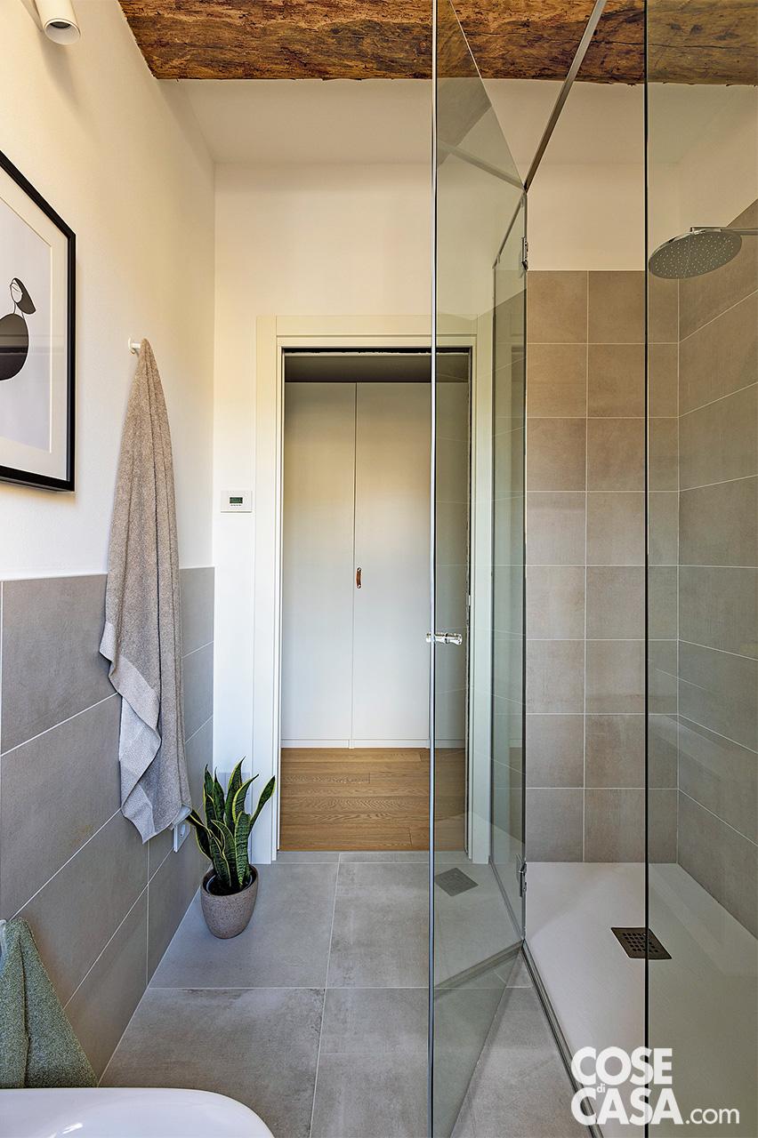 Nel bagno i rivestimenti a terra e a parete sono in lastre di gres porcellanato grigio della coll. Reside di Iris Ceramica. Nel box doccia, il soffione è Titis di Bossini. I sanitari sono della serie Icon di Geberit. Gli asciugamani sono di Fazzini.